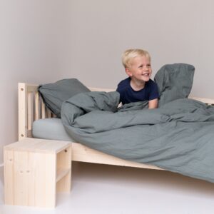 Zitten in het eenpersoons kinderbed met brede lach