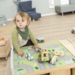 Betzold tapijt voor een speeltafel op de vloer - set van 2 - jongentje zittend aan speeltafel met tapijt van de stad en auto's op tafel