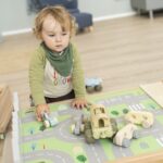 Betzold tapijt voor een speeltafel op de vloer - set van 2 - spelend jongentje met auto's op tapijt van de stad met losse auto's