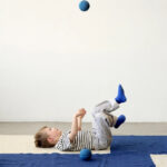 Foam Ball Deep blue - Sky blue jongentje liggend op de grond en bal in de lucht
