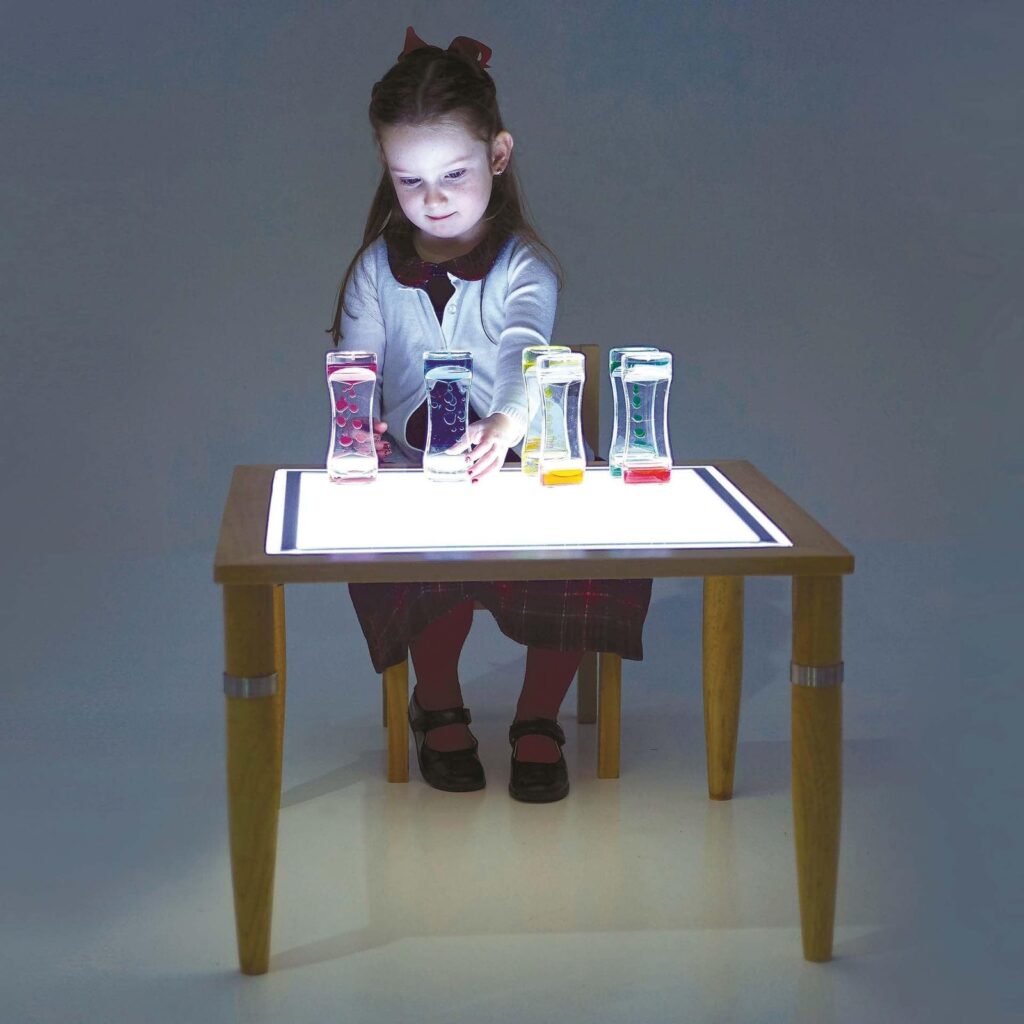 Kind speelt met lichtdoorlatende materialen op de houten Tickit lichttafel